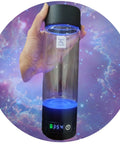 Hand holding Portable Hydrogen Water Bottle Generator For Everyday Hydration Hack With Purifying Tech, Glass BPA Free Bottle against galaxy background