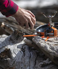 Ultralight Camping Stove That Boils Water In About 3 Minutes on a log, showing its compact design and stability for easy outdoor cooking.