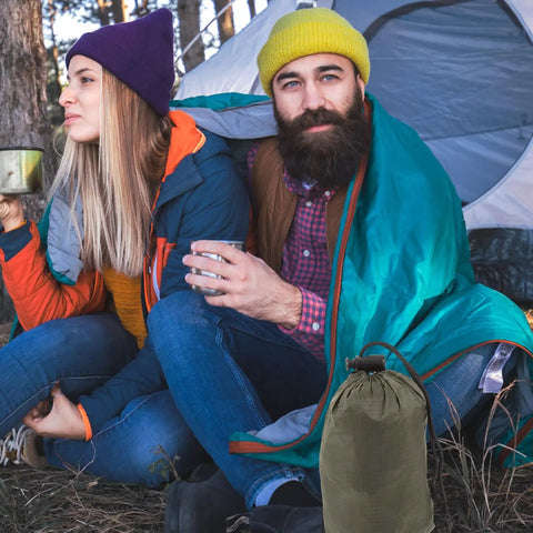 Couple using Emergency Blanket Set With Green Aluminum Thermal Rescue Blanket And A Carry Bag For Camping And Hiking Survival Warmth