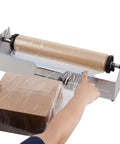 Heavy Duty Stainless Steel Tabletop Stretch Film Dispenser With Smooth Slide Cutter For 16 To 26 Inch Plastic Wrap Rolls in use wrapping a box.
