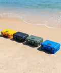 Four waterproof hard cases for DJI Mini 4 Pro Mini 3 Pro and RC transmitters in yellow, black, green, and blue on a beach.
