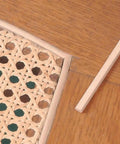 Quarter Inch Reed Spline For Cane Weaving Chair Repair cream finish next to woven paper cane, demonstrating tapered shape for smooth fit.