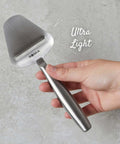 Hand holding Stainless Steel Cheese Slicer Copenhagen Multifunctional Kitchen Tool For All Types Of Cheese Grating close-up