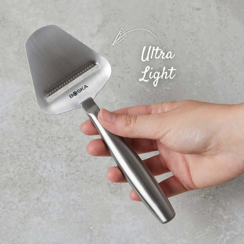 Hand holding Stainless Steel Cheese Slicer Copenhagen Multifunctional Kitchen Tool For All Types Of Cheese Grating close-up