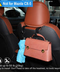 Behind car seat with headrest hooks holding a pink handbag and blue umbrella, not compatible with Mazda CX-5.