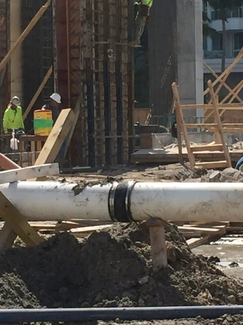 Construction site with pipe secured by 304 stainless steel band 1 inch wide 0.044 inch thick with clamps for tough tie downs