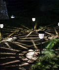 Lit Solar Path Lights 4 Pack Waterproof Metal Outdoor Lights illuminating a nighttime walkway with glass and stainless steel housings.