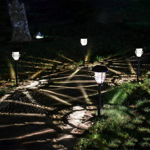 Lit Solar Path Lights 4 Pack Waterproof Metal Outdoor Lights illuminating a nighttime walkway with glass and stainless steel housings.