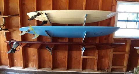 Dude Approved Surfboard Wall Mount Rack With Padded Arms Holds Four Shred Ready Boards Adjustable Height with three surfboards displayed.