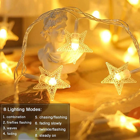 Close-up of 33 Ft 100 LED Star Fairy String Lights With Remote And Timer For Indoor And Outdoor Use, warm white glow around statue.