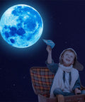 Child in aviator cap below glowing blue moon from 1088 Piece Glow In The Dark Stars And Moon Wall Decals Kit For Kids Room Ceiling Night Sky Decor
