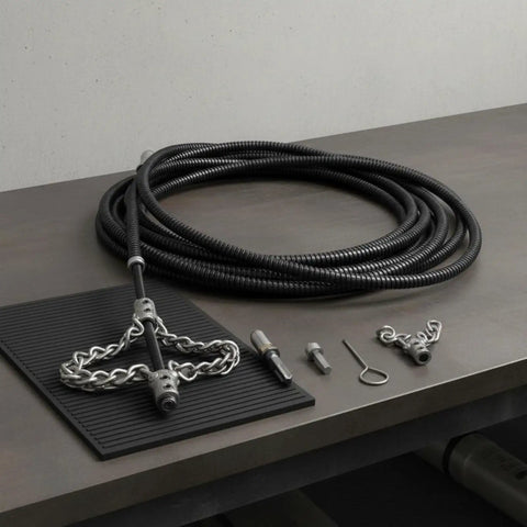 Heavy Duty Flexible Chain Knocker Drain Snake Auger With Solid Steel Core to knock out stubborn clogs and scale buildup laid on a table.