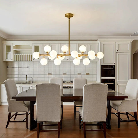 Mid Century Modern Sputnik Chandelier With 16 Lights Brushed Brass Arms And Frosted Milk Glass Shades For Kitchen Or Dining Room hanging above a dining table.