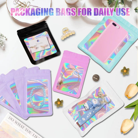 Colorful holographic packaging bags with clear windows, showcasing jewelry and small gifts, flat lay with flowers and accessories.