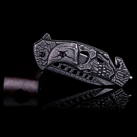 Pocket Folding Knife With 3D Skull Embossed Handle And Razor Sharp 440 Stainless Steel Blade, closed view on black background.