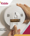 Close-up of hardwired smoke and carbon monoxide detector with open battery door and Kidde branding