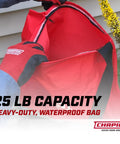 Person wearing gloves holding a red 25 Pound Capacity Handheld Seed Spreader With Waterproof Bag Enclosed Gears Rear Baffle Adjustable Shoulder Strap And Multiple Spread Settings Red For Lawn Garden And Backyard Use.