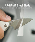 Close-up of Spud Small Neck Knife with AR-RPM9 Steel Blade cutting paper, aluminum handle in raw silver.