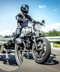Motorcycle on road zoom-in showing Two Pack Motorcycle Bell Set With Gift Box And Legend Card, Weatherproof Badass Good Luck Charm For Riders.