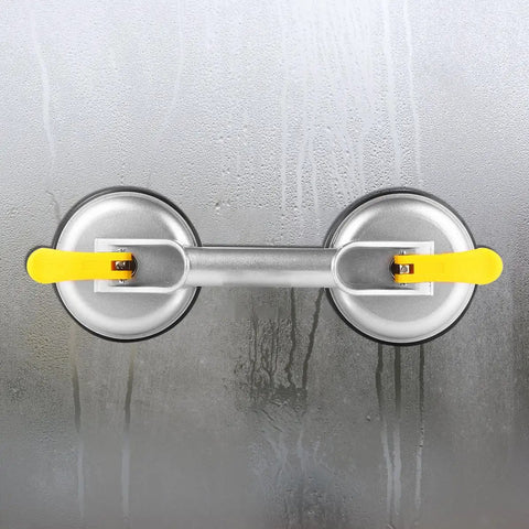 Super Heavy Duty 2 Jaw Glass Suction Cup Lifter Tool With Spring Loaded Locking Handle, aluminum and rubber, on wet surface.