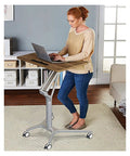 Woman using Adjustable Mobile Overbed Table Featuring Smooth Rollin Casters And Beastly Stable Base for remote work.