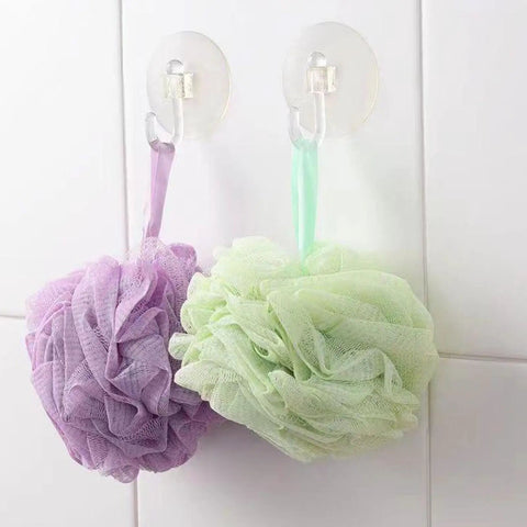 Super Strong Suction Cup Hooks For Bathroom Wall 10 Pack holding purple and green bath loofahs on a smooth white tile surface.