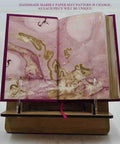 Open leather-bound book on stand, showing unique marbled paper, "From Raw Wool To Finished Goods: A Rugged Premium Leather Bound Guide To Wool"
