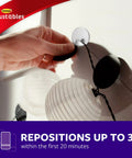 Repositionable Wall Decor Clip Kit With 8 Spring Clips And 24 Mini Squares, White Finish, being adjusted on a wall.