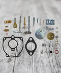 Beefed Up Carburetor Repair Kit For 656 706 756 Tractor with shafts, gaskets, and float components displayed on wood surface.