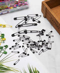 Kickass Assorted Steel Safety Pins Bulk Kit For Sewing Tailoring And Crafting Durable Multi Purpose Badge Clips and black safety pins scattered on a table