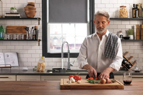 Man preparing food in modern kitchen featuring VoiceIQ Activation Module for Touch2O Kitchen Faucets Compatible with Alexa and Google Assistant Voice Control Smart Home Upgrade Kit EP100855 Easy Setup and Hands Free Kitchen Control.