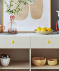 Cabinet with yellow knobs, art, and decorative items displayed in a modern room setting.