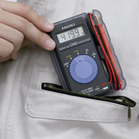 Person holding Card Size HiTester And Digital Multimeter With 41.99 Megaohms Resistance 500 Volts AC DC Range showing 419.9V reading.