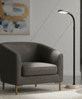 Adjustable Floor Lamp With Bendable Neck for Bedroom And Living Room next to armchair, woodgrain base in a modern setting.