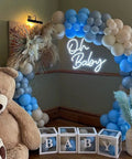 Neon Sign for Baby Shower Backdrop LED Light Up Wall Decor 21.5 Inch By 20 Inch Great for Gender Reveal Birthday Party Decorations Oh Baby Theme next to blue and white balloon arch with teddy bear.