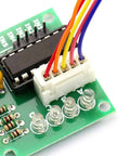 Close-up of 28BYJ-48 stepper motor driver board with ULN2003 on green PCB, white 5-pin header and color-coded wires