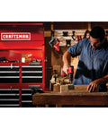 Man using V20 Cordless Drill and Driver Kit Half-Inch Brushless Motor 350 UWA Two-Speed in workshop with tools in background.