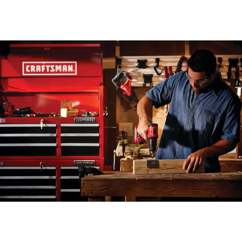 Man using V20 Cordless Drill and Driver Kit Half-Inch Brushless Motor 350 UWA Two-Speed in workshop with tools in background.