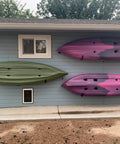 Big Time Heavy Duty 4 Pack Kayak Storage Racks Wall Mount Hangers For Canoe Paddleboard SUP And Snowboards Durable Steel Rack System holding green and pink kayaks on a blue wall.