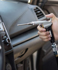 Hand using High Flow Air Blow Gun With Three Piece Pneumatic Nozzle Kit For Dust Debris And Wet Spills on car dashboard.