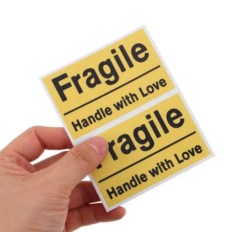 Yellow Fragile Stickers For Small Business Packaging 6 Pack High Visibility PVC Adhesive Labels For Shipping Moving Warehouses Parcels Luggage And Handling Durable Fragile Warning Signs For Safe Delivery, hand holding two labels