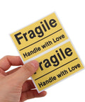 6 Pack Yellow PVC Fragile Shipping Labels with Adhesive Warning Stickers for Moving Boxes and Warehouses, High Visibility Packing Labels for Efficient Shipping and Handling, Bulk Package Stickers, hand holding two labels