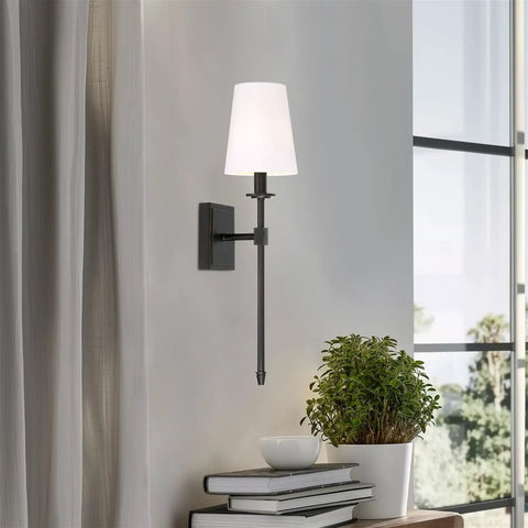 Dope Mid Century Modern Wall Sconce 20 Inch Tall With Oil Rubbed Bronze Finish And White Linen Shade Candle Style Wall Light for Bathroom or Powder Room Accent Lighting in a living room setting.