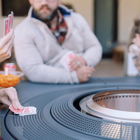People playing cards around the Surround Extend For Bonfire Ranger Fire Pit Table Space Upgrade Outdoor Backyard Party Accessory.