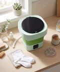 Laundry Day No Sweat With This 6L Folding Portable Washing Machine on a countertop with socks and detergent.