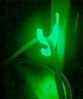 Glow In The Dark 2 In 1 Universal Hook Set For Industrial Storage Racks 55 Lb Capacity 15 Pack Tough Green Plastic For Garage Shelves And Workshop Organization glowing in dim light with a cable hanging from it.
