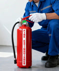 Person using a red fire extinguisher, demonstrating safety equipment handling.