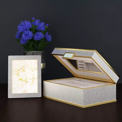 Open glittered jewelry box, silver frame with floral picture, blue flowers in vase