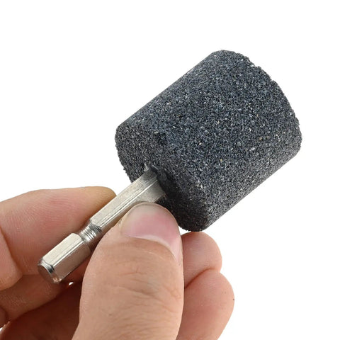 Close-up of a hand holding a cylindrical grinding stone from the Eight Piece Pro Grade Aluminum Oxide Mounted Grinding Stones Set With One Quarter Inch Hex Shank For Electric Rotary Tools Drills And Grinders Cone And Cylindrical Shapes For Precise Grinding Shaping And Deburring.