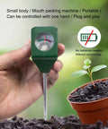 Hand holding a Single Probe Soil PH Meter For Garden And Lawn Care, Battery-Free Portable PH Tester near potted plant in moist soil.